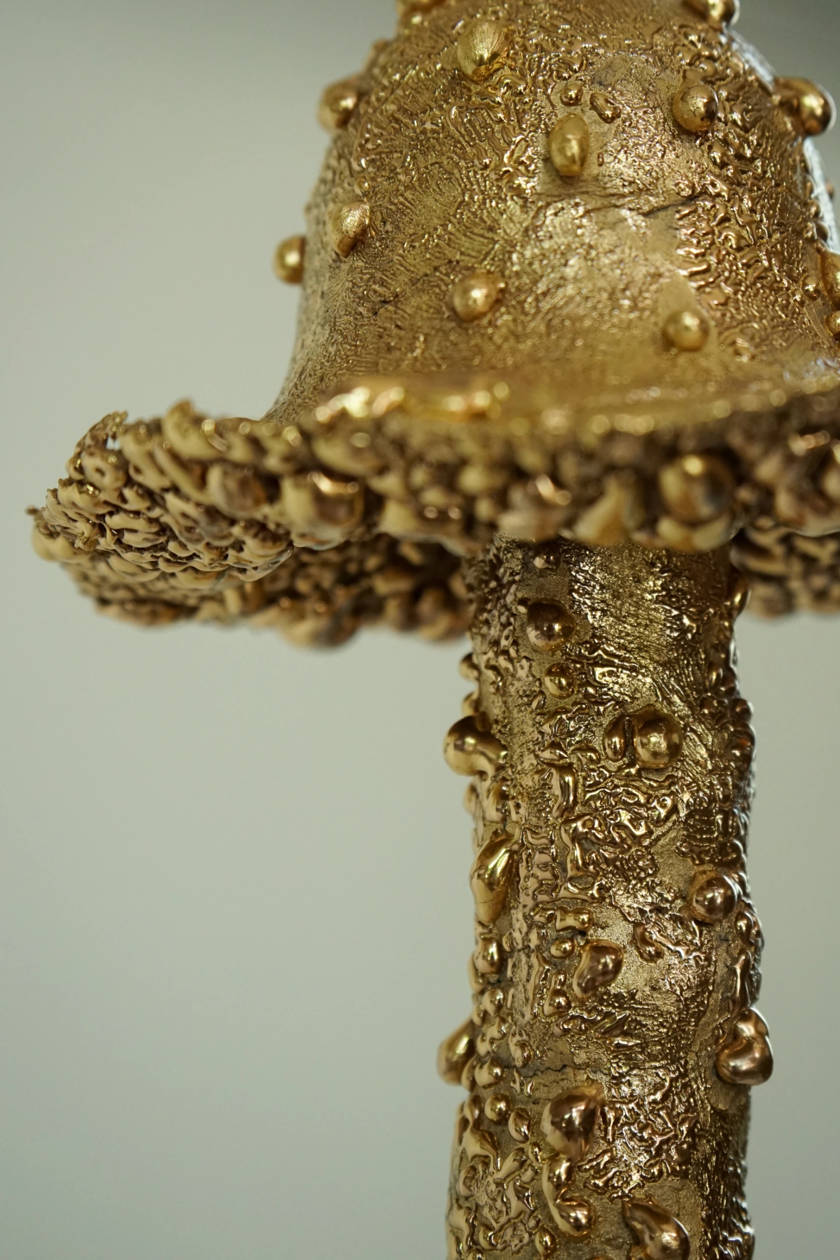 Gold Roundhead (2026), ceramic sculpture by Sjors Driessen with a tall elongated mushroom-like form covered in textured glaze and reflective gold lustre.