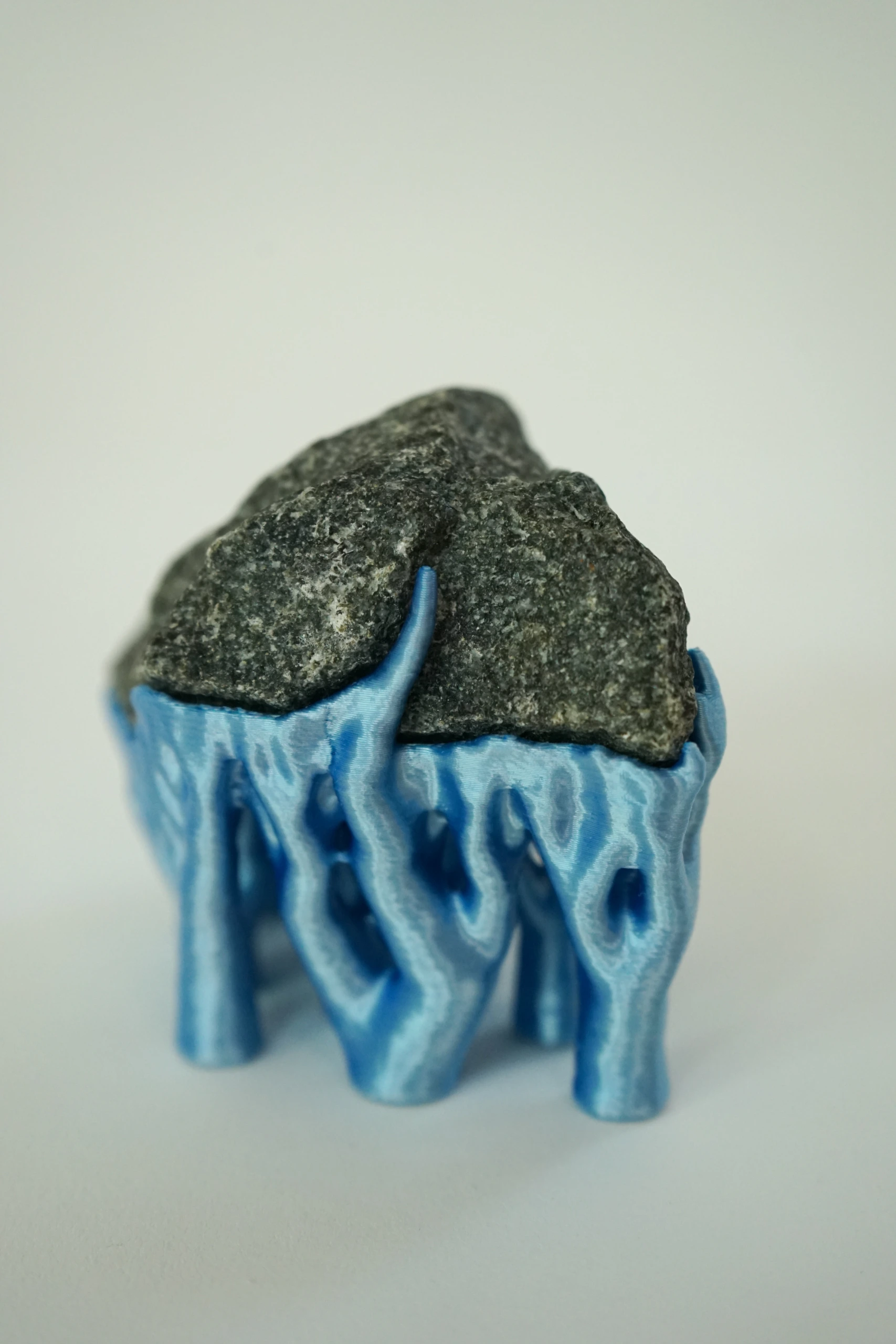 Blue Hyphae III (2026), sculpture by Sjors Driessen with three dark olivine diabase stones supported by bright blue branching hyphae-like structures.