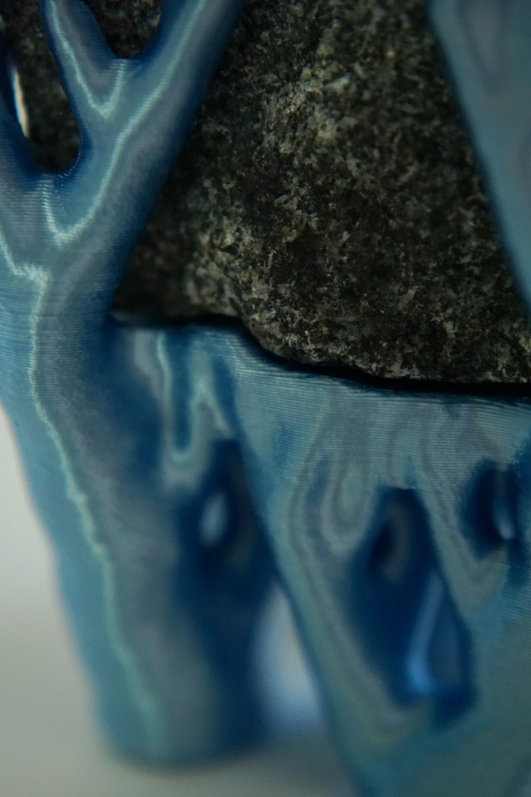 Blue Hyphae III (2026), sculpture by Sjors Driessen with three dark olivine diabase stones supported by bright blue branching hyphae-like structures.