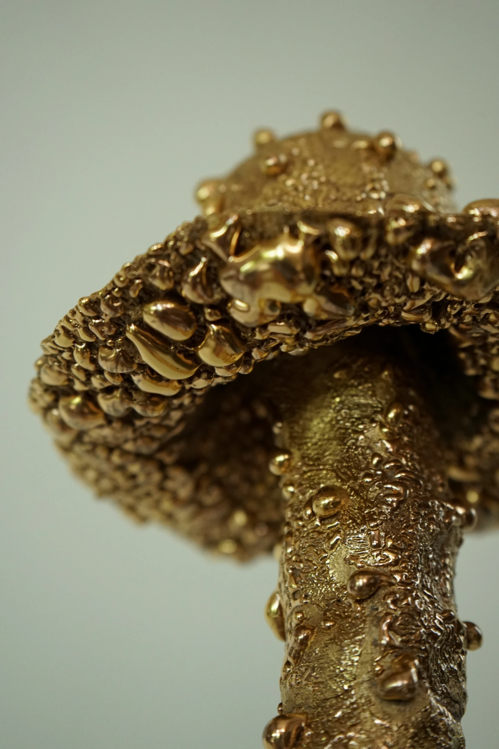 Gold Roundhead (2026), ceramic sculpture by Sjors Driessen with a tall elongated mushroom-like form covered in textured glaze and reflective gold lustre.