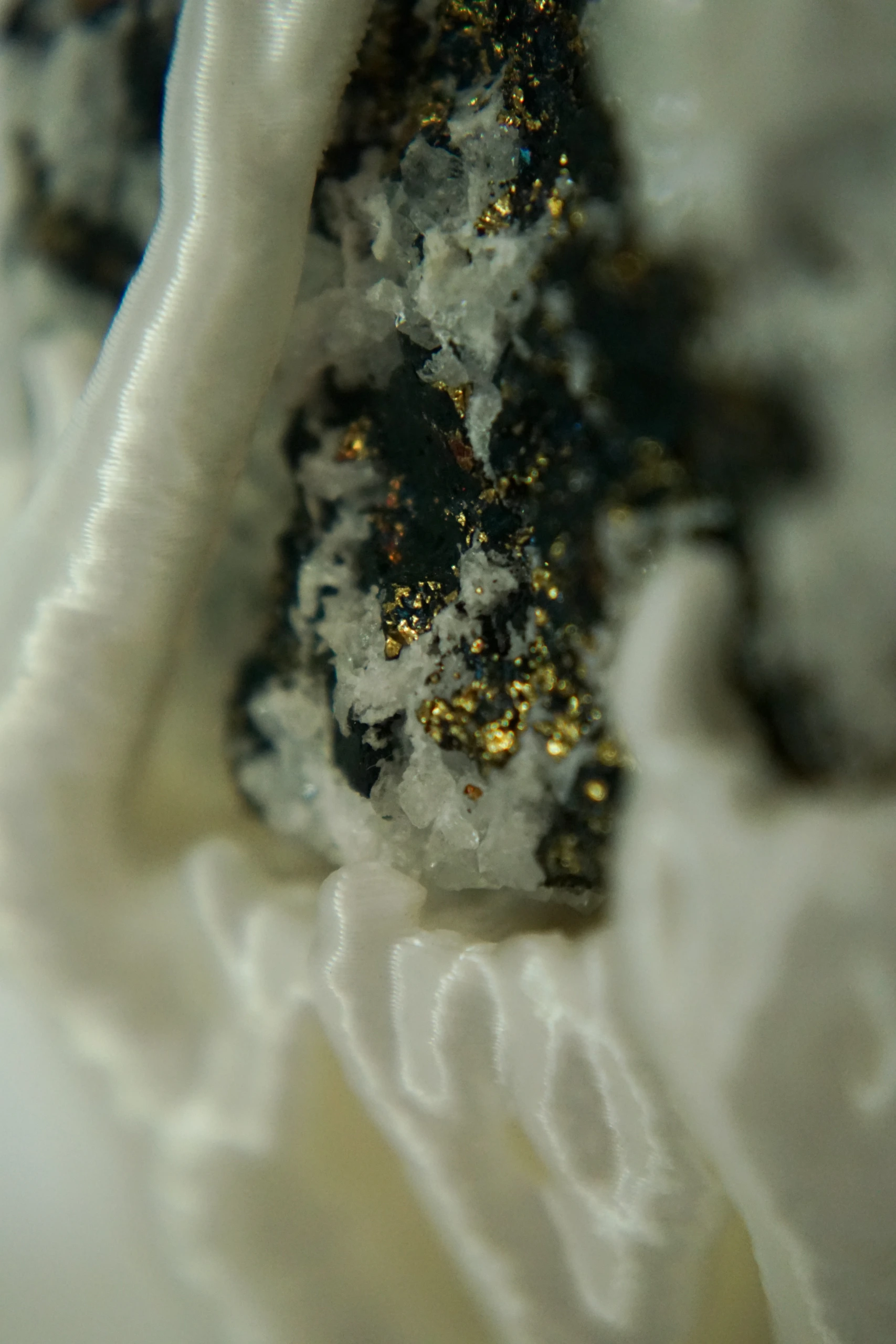 Mineral Cradle, sculpture by Sjors Driessen with a quartz-rich natural stone containing dark and metallic mineral inclusions, held by white branching hyphae-like structures.