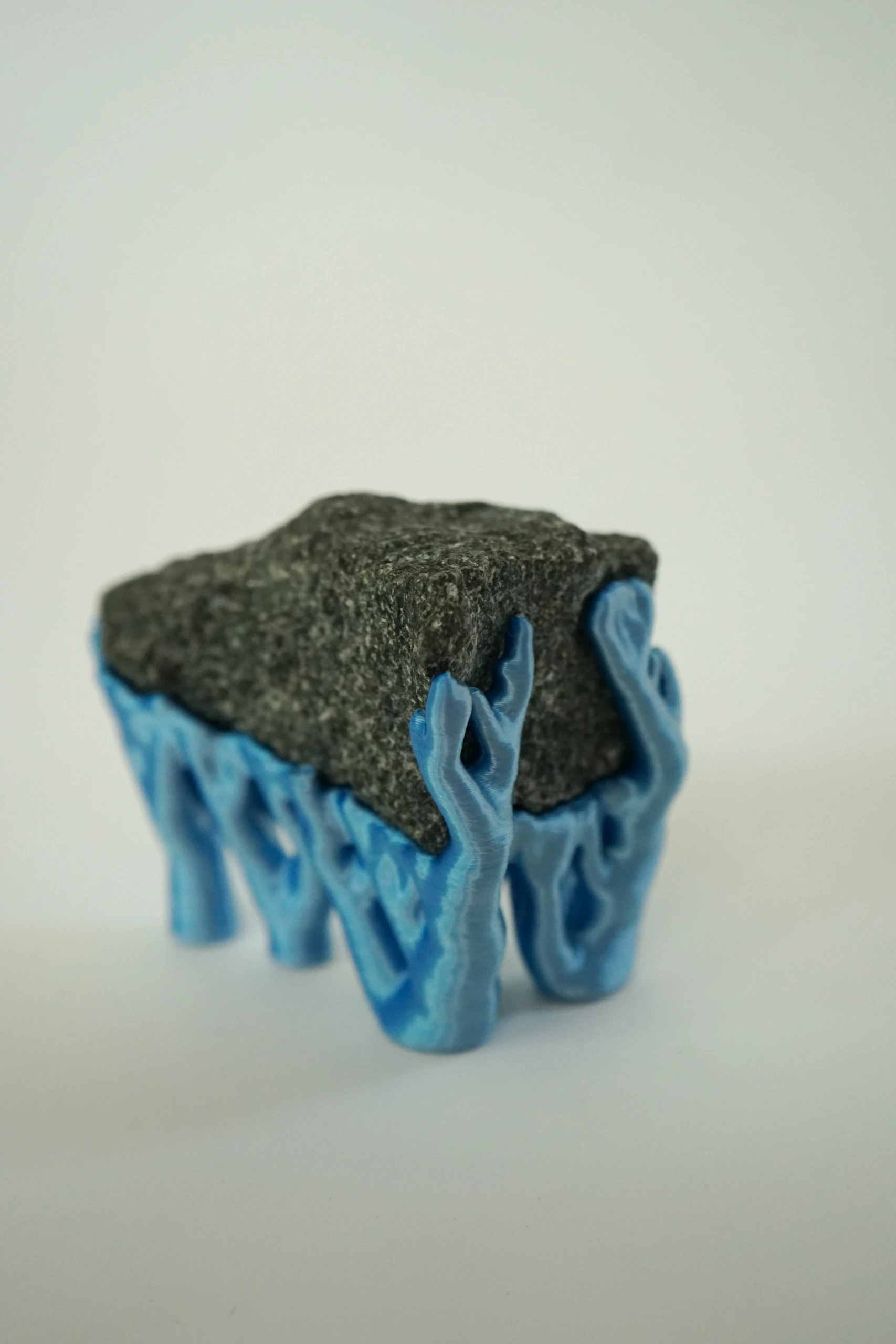 Blue Hyphae III (2026), sculpture by Sjors Driessen with three dark olivine diabase stones supported by bright blue branching hyphae-like structures.