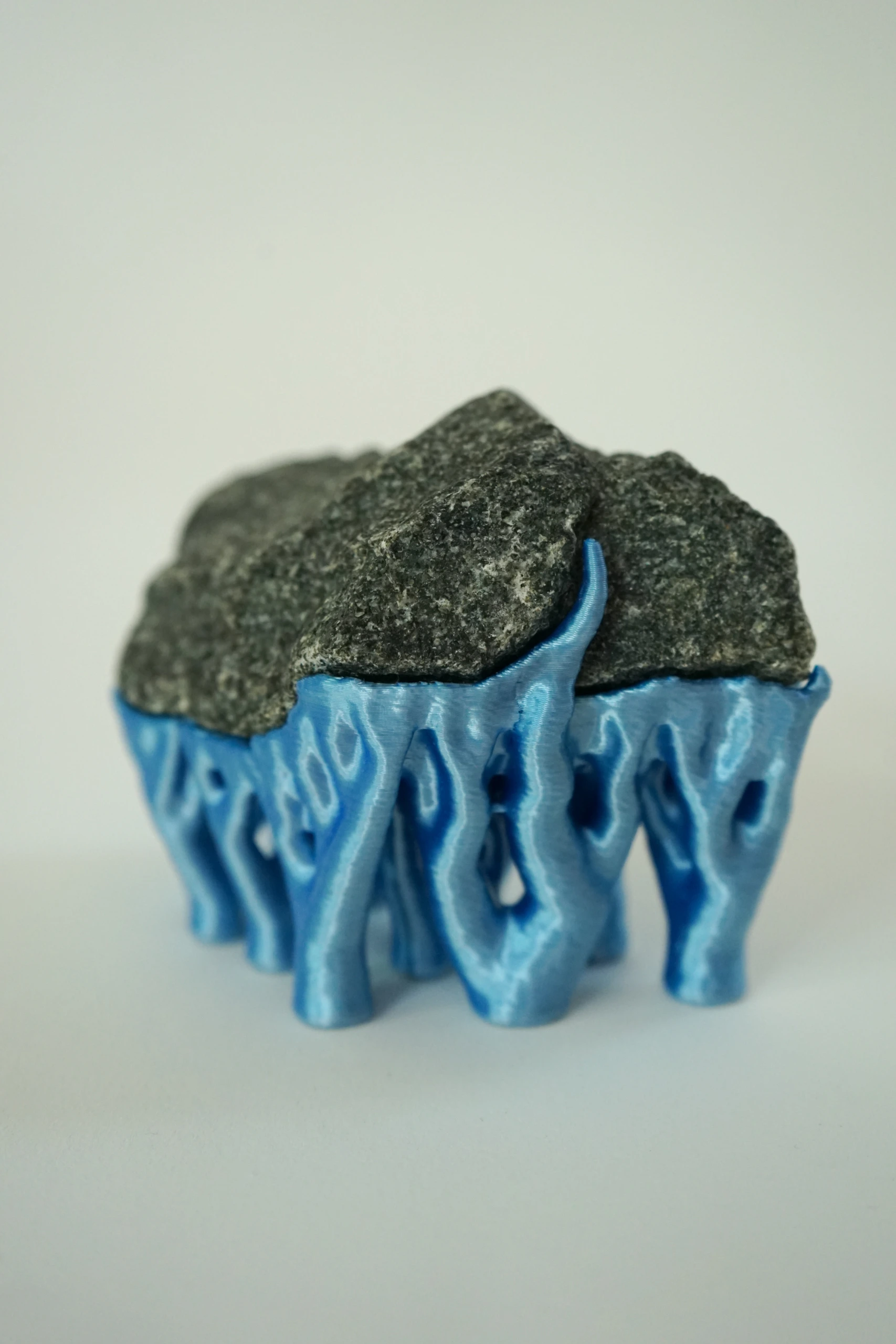 Blue Hyphae III (2026), sculpture by Sjors Driessen with three dark olivine diabase stones supported by bright blue branching hyphae-like structures.