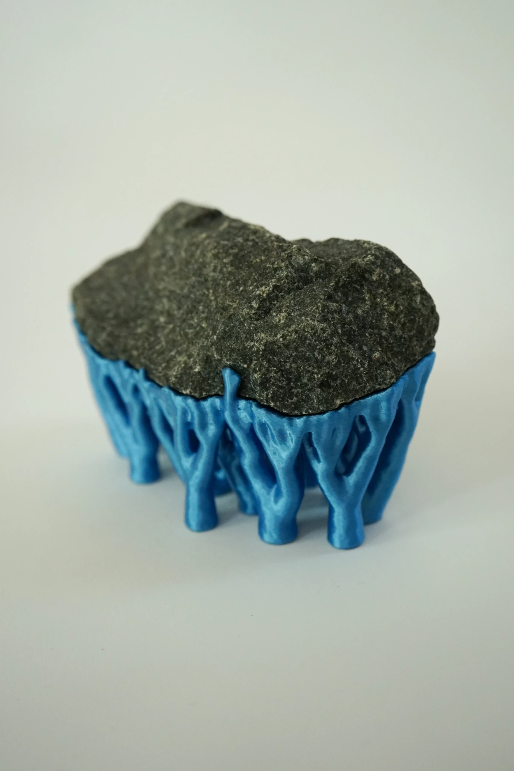 Blue Hyphae III (2026), sculpture by Sjors Driessen with three dark olivine diabase stones supported by bright blue branching hyphae-like structures.