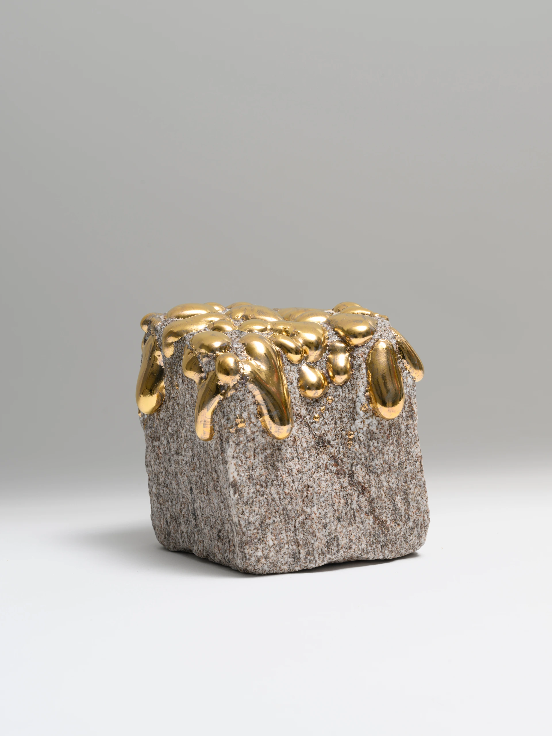 Lucky Tears (2025), granite sculpture by Sjors Driessen with glossy gold glazed drops flowing over a rough stone form.