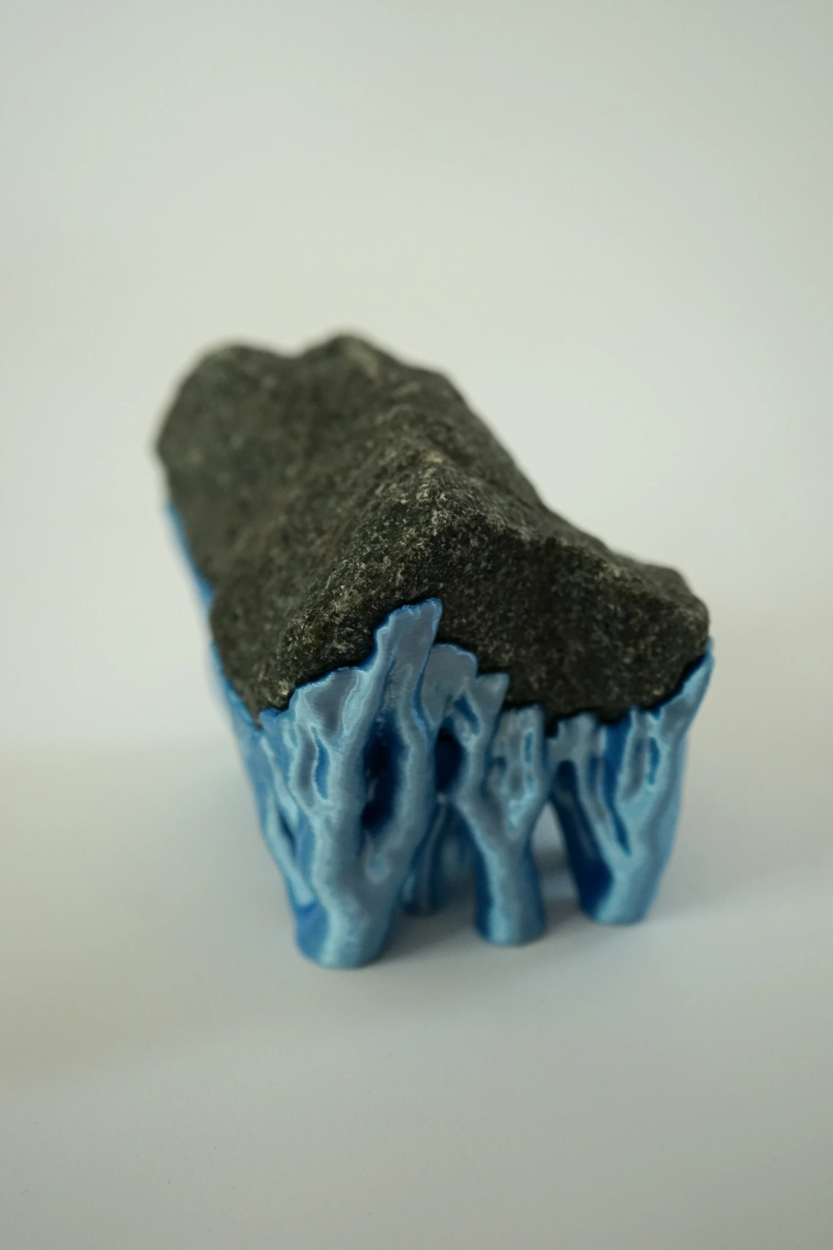 Blue Hyphae III (2026), sculpture by Sjors Driessen with three dark olivine diabase stones supported by bright blue branching hyphae-like structures.