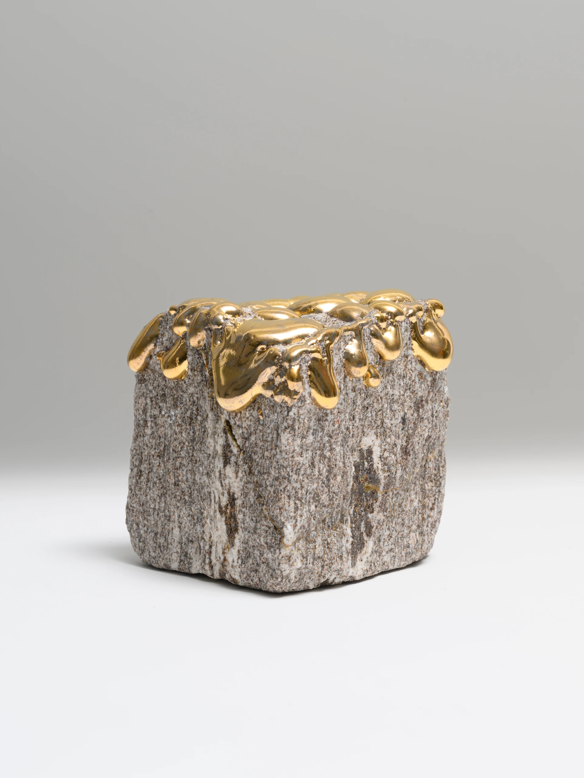 Lucky Tears (2025), granite sculpture by Sjors Driessen with glossy gold glazed drops flowing over a rough stone form.